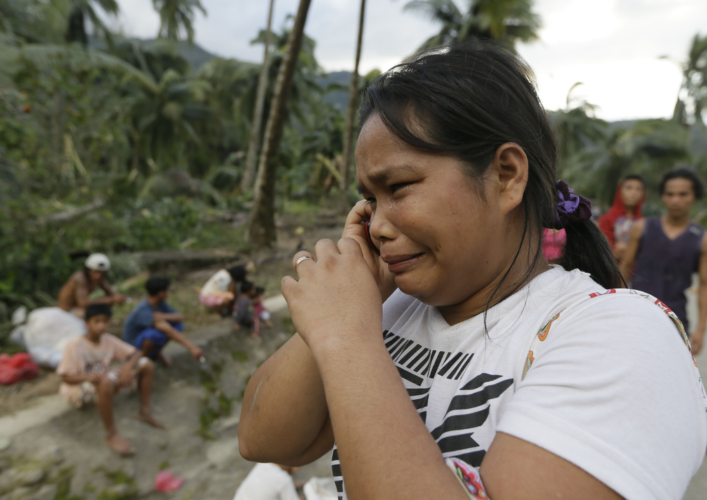 Rosalinda Pasko tearfully breaks the news to a relative of the death of her two of her family members at the flash flood–hit village of Andap, New Bataan township, Compostela Valley in southern Philippines, Dec. 5, 2012.