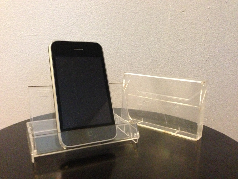 To make an iPhone stand, fold an old cassette case backwards so it props itself up on a table.
