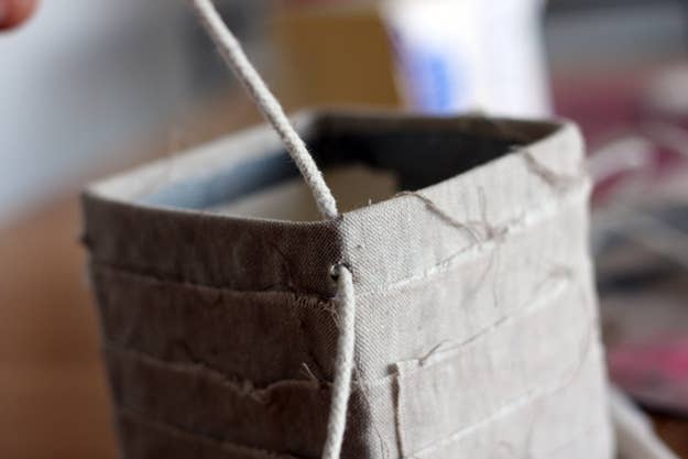 Tie a knot with both pieces of string just above the top of the box. Repeat the same process on the other 3 corners.