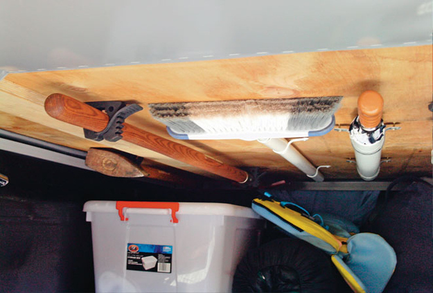 Brackets holding supplies like broom, mop, umbrella on the ceiling of a van for space-saving storage