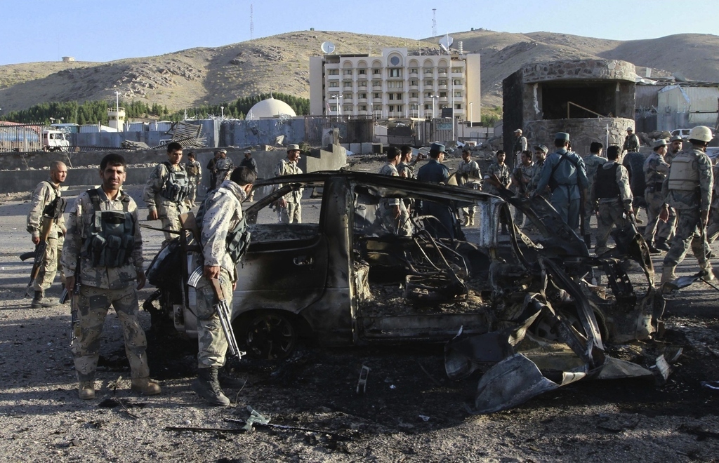 Afghan security forces inspect a damaged car used in a suicide bomb attack outside the U.S. consulate in Herat.