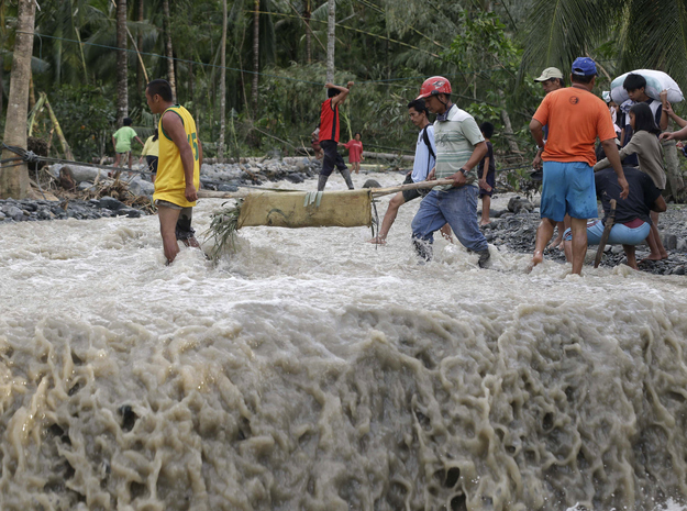 Residents cross a river with the body of a child after retrieving it from the flash flood–hit village of Andap, in New Bataan township, Compostela Valley in southern Philippines, Dec. 5, 2012, a day after the devastating Typhoon Bopha made landfall.