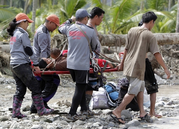 A pregnant woman, who survived flooding, holds her child on a stretcher while being evacuated in New Bataan town in Compostela Valley in southern Philippines, Dec. 6, 2012.