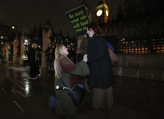 Elizabeth Maddison (left) proposes marriage to her civil partner Hannah Pearson in front of Parliament in London, Feb. 5, 2013. British lawmakers on Tuesday backed legalizing gay marriage in the first of several votes on the issue after a debate that split Prime Minister David Cameron's ruling Conservative party in two.