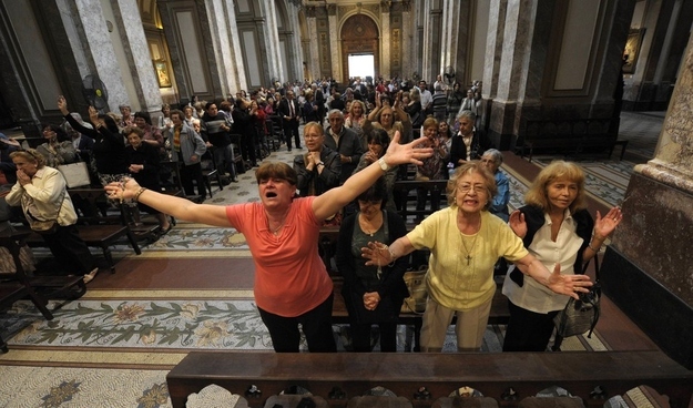 Catholics at Metropolitan Cathedral in Buenos Aires raise their hands toward the sky.