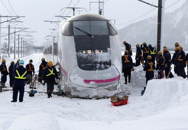 Railway workers and investigators inspect the bullet train the morning after it derailed.