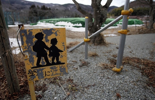 A warning sign beside a roadway, near a pile of radiation-contaminated soil at the Tsushima Junior High School in Namie.