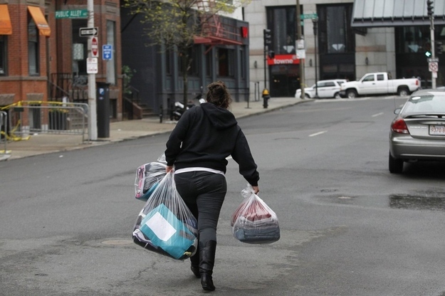 A girl carries bags of laundry up a side street near Boylston Street as residents and business owners are allowed to return to the street for the first time.