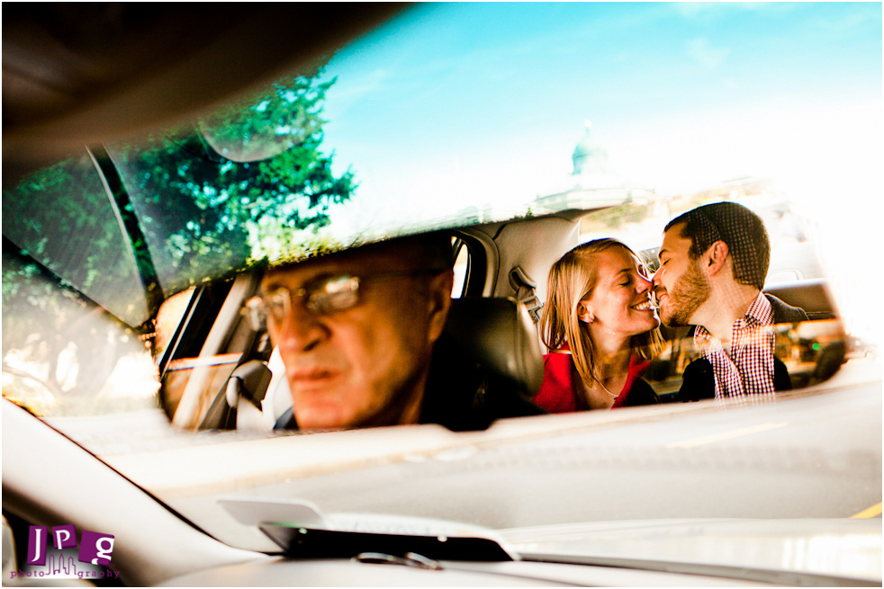 This couple sneaks a quick kiss behind their taxi driver.