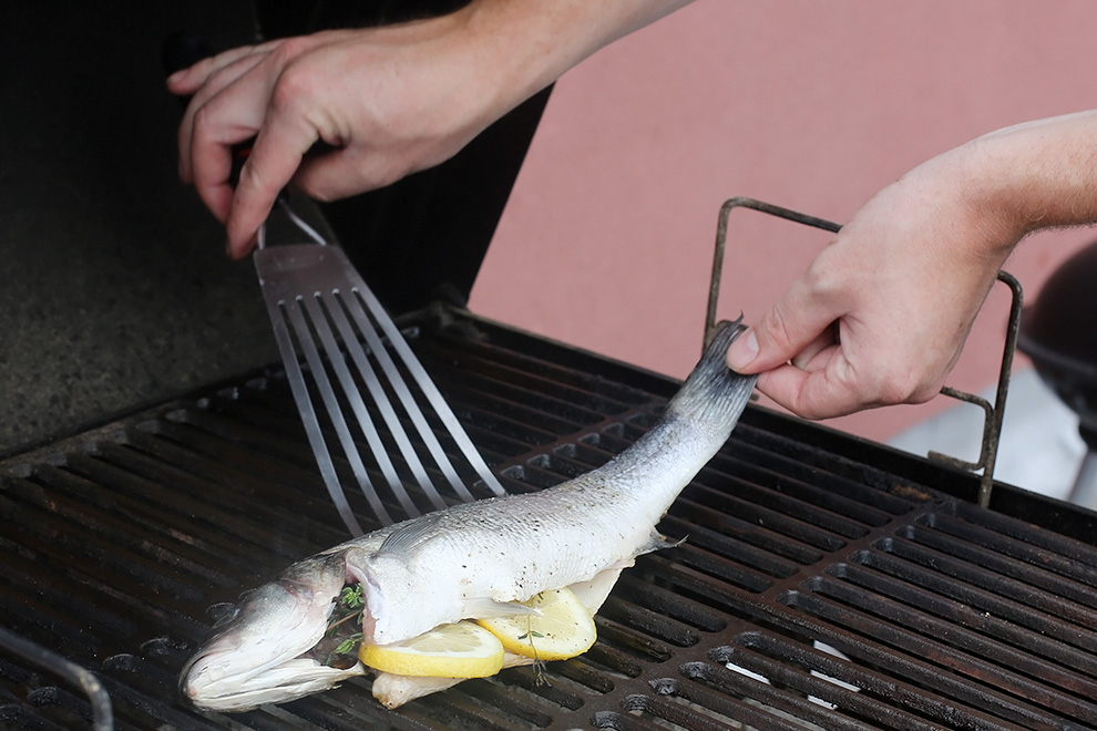 Flipping a whole fish is easiest if you're not afraid to use your hands. Put some olive oil on your spatula (don't use tongs), then gently slide it under the tail toward the head lengthwise (lifting the tail with your fingers if you need to). With your fingers securing the fish flat on the spatula near the gills, gently pick it up and flip. If you mangle the skin a little bit on your first try, it's okay—it'll still be delicious. Long, thin, metal spatulas make this easiest (they're called "fish spatulas" in the store for a reason). If you start grilling fish all the time, you can also consider trying a mesh fish basket, which makes flipping as easy as possible (and is great for doing a big batch of small fish like sardines). But seriously, you can do this with just a spatula and your hands.