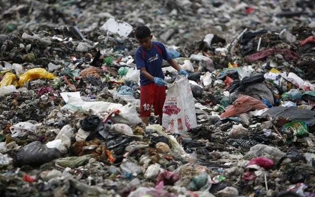 A boy, surrounded by a pile of trash, scavenges for plastic for recycling at a garbage dump site in Bachok, 550 kilometres (342 miles) northeast of Kuala Lumpur September 7, 2012. The garbage collector makes about 150 ringgit ($48) a day.