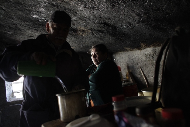Santa Martha de la Cruz Villarreal (R) looks on as her husband Benito Hernandez pours hot water into a cup while standing inside their home near San Jose de Las Piedras.