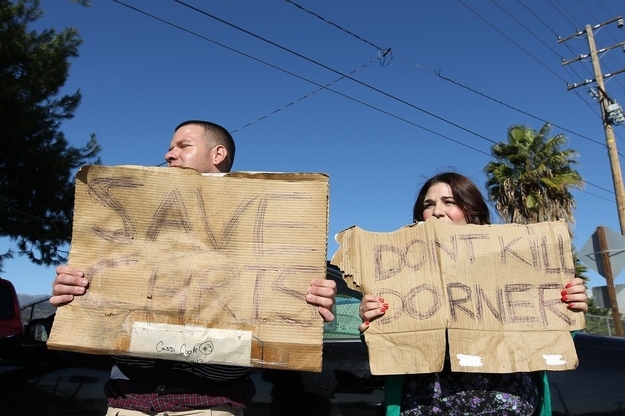 Frank Cardiel (L) and Shantel Cardiel hold up signs in support of fugitive triple murder suspect Christopher Dorner along the road in San Bernardino, California on February 12, 2013. Fugitive former US cop Christopher Dorner exchanged gunfire with police near a Californian ski resort where his burnt-out truck was found, reports said. The 33-year-old was involved in the shooting after he tried to burglarize a home near Big Bear, two hours east of Los Angeles, the Los Angeles Times reported, citing a law enforcement source.