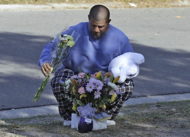 Jeremy Bush, brother of Jeff Bush, places flowers and a stuffed animal at a makeshift memorial in front of the home.