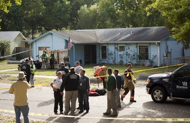 A crowd gathers at the home of Jeff Bush after he was consumed by a sinkhole while lying in bed on the night of March 1, 2013 in Seffner, Florida. First responders were not able to reach Bush after he disappeared and now say it is a recovery mission.