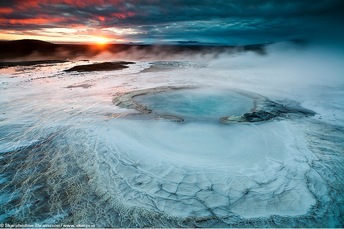 Geothermal activity in Hveravellir, central highlands of Icelandby Skarphéðinn Þráinsson“The colored surface is rich with silica minerals among other geothermal materials making this unique hotspring area one of the most spectacular sights in Iceland. In 1960 Hveravellir was made one of the protected nature reserves of Iceland.“During this late summer sunrise I was lucky to have some wind blowing most of the steam away from the hotsprings, to capture the texture of the surface and also include the Hofsjökull glacier in the background.“Iceland’s most famous outlaw Fjalla-Eyvindur was maybe the first to discover Hveravellir, when hiding in the highlands of Iceland for about 20 years, after stealing some sheep from farmers. He was clever to make use of the geothermal area to survive the cold winter in Iceland.” – Skarphéðinn ÞráinssonView more of Skarphéðinn’s photography at his website, or visit his Flickr page.