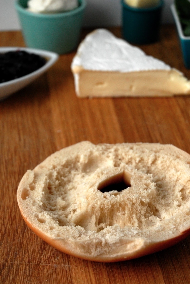 Dig out anywhere from half an inch to an inch from the center of your bagel (depending on how big it is). Do this for both halves of the bagel for maximum deliciousness.You are now free to fill the trench with whatever toppings you might desire, such as, say, brie cheese, mascarpone, and blueberry jam to make the best grilled cheese bagel ever.