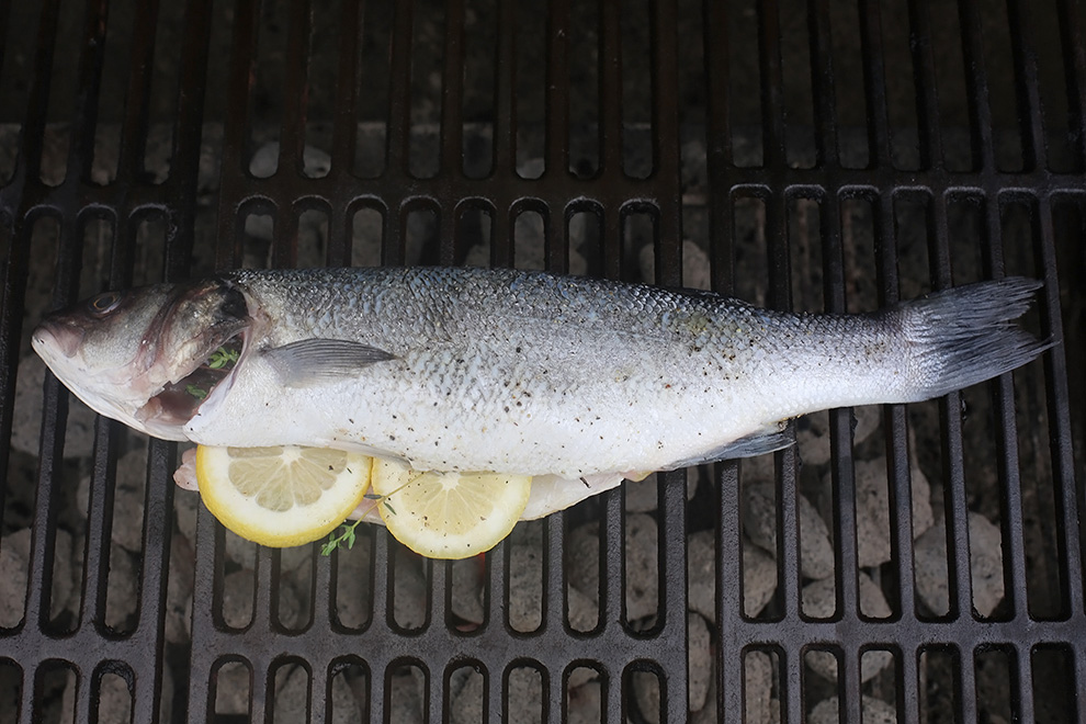 As the fish's oils hit the coals as it cooks, you may see a few flare-ups. Don't worry if these are small flames—they'll make the skin extra crispy and delicious. If there is a lot of fire, use a thin jet of water from a spray bottle to zap the spots of burning oil on the coal bed. Not too much water, though, or your coals will cool down.