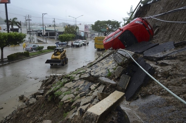 A car lies on its side after a portion of a hill collapsed due to heavy rains in Acapulco.