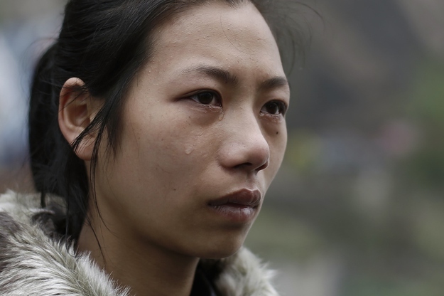 Yang Huan cries while waiting for workers to clear a landslide, in which she believes her husband is buried.