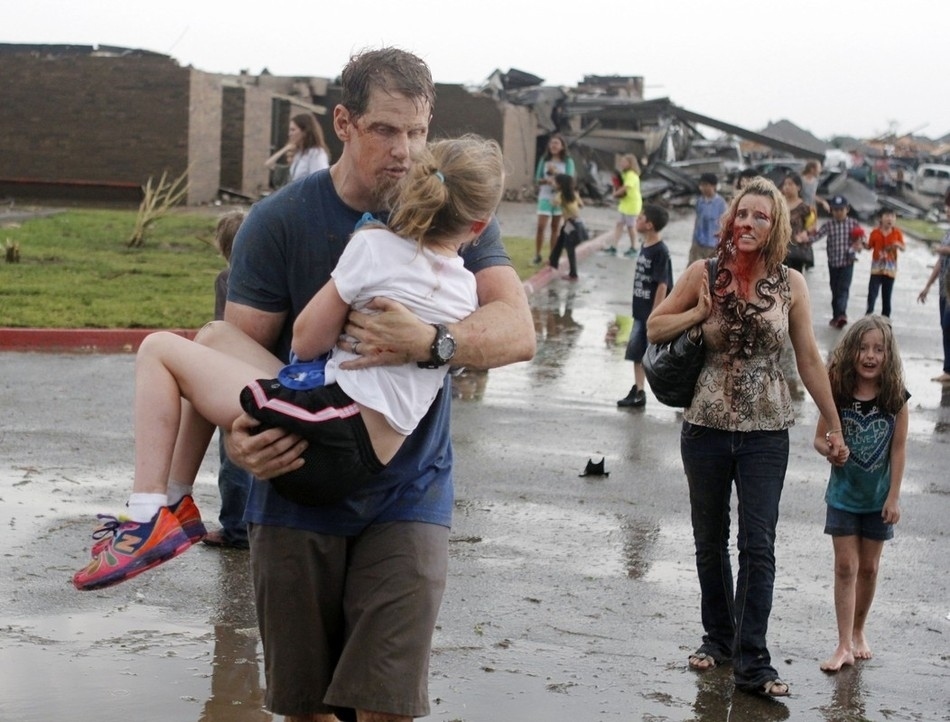 Originally believed to be teachers carrying and guiding students away from the after math of debris that became Briarwood Elementary after the tornado hit, it was later learned that Steve and LaDonna Cob -- parents -- had gone to the school as the tornado bared down, they told CNN.The Oklahoman newspaper photographer Paul Hellstern told CNN he'd arrived in the destroyed neighborhood -- later determined to be EF-5 destruction -- roughly 5 minutes after the tornado swept through and began snapping pictures of the "children pouring out.""It was pandemonium, with children crying everywhere, bloody teachers and so forth."LaDonna was, in fact, a teacher at Brairwood Elem., but she had the day off and had only gone to the school with Steve because of the storm, she told CNN. "Him, and I, and the teacher, just jumped on top of the kids and rode it out there."Hellstern snapped the picture of the family as the emerged from the school.