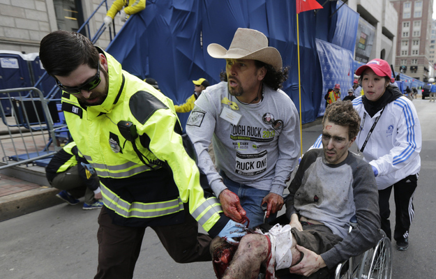 An emergency responder and volunteers, including Carlos Arredondo, in the cowboy hat, push Jeff Bauman in a wheelchair after he was injured in one of two explosions near the finish line of the Boston Marathon.