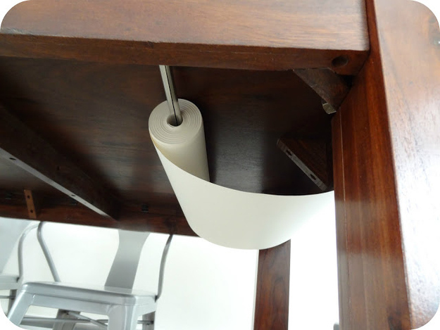 Add a tension rod to the underside of a table for a paper roll.