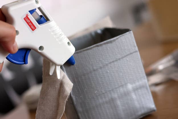 Put some duct tape on the bottom side of the box to tape down the pieces of fabric to the base for added security.