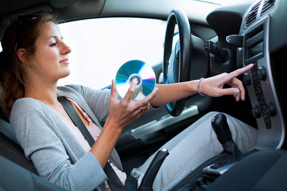 Car playing Music. Girl listen Music in car. Девушка держит компакт диск.