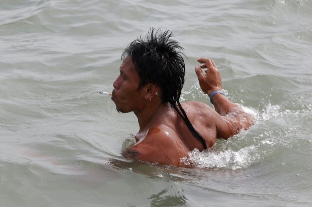 A fisherman smokes a cigarette as he assists in searching for victims of Friday's ferry disaster during rescue operations.