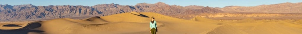 Alisha walks across sand dunes.