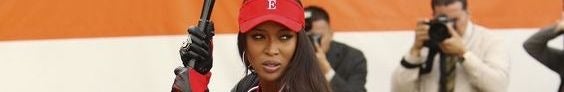 An extreme close up of Naomi Campbell playing baseball in a red cap