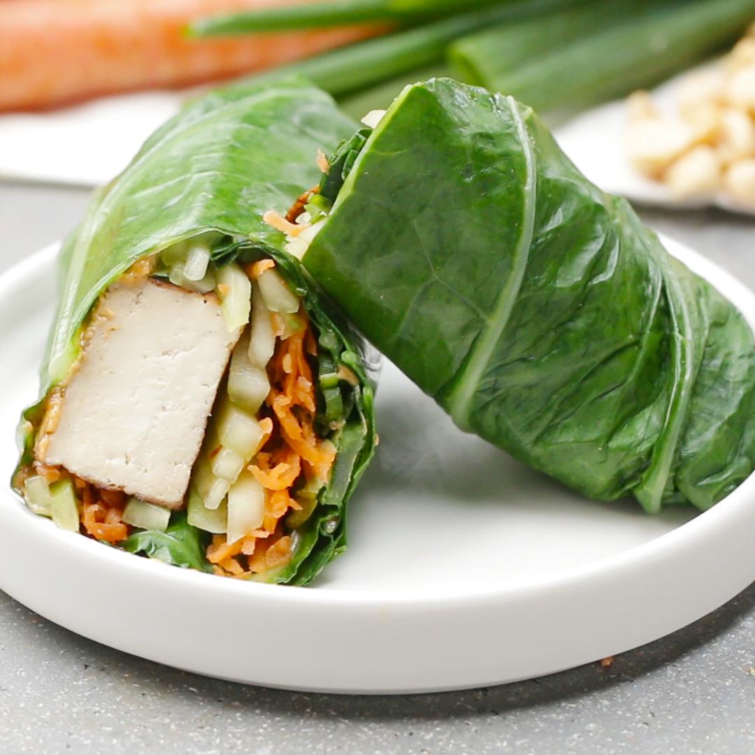 Leaf-wrapped veggie and tofu wrap sliced in half, with visible carrots and cucumber on a white plate