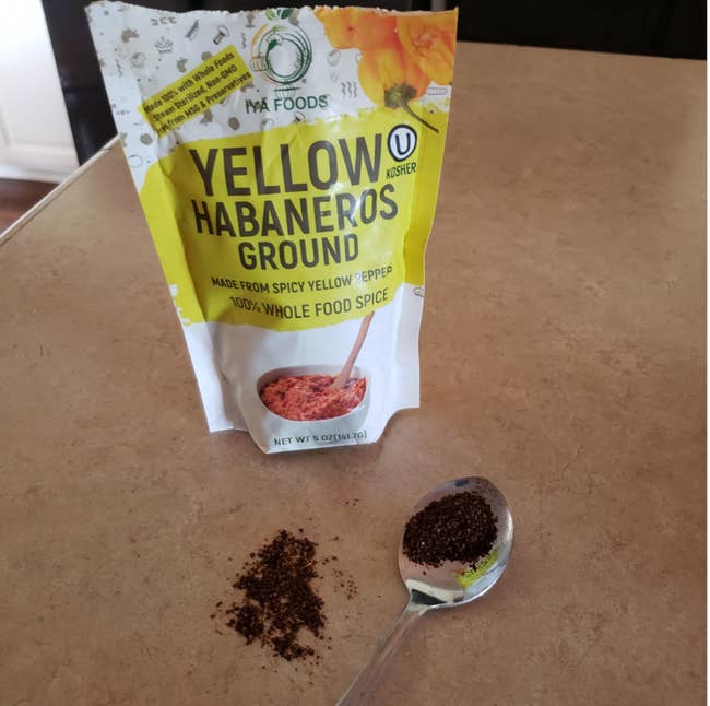 A bag of powdered habanero open with a spoonful of it on the counter 