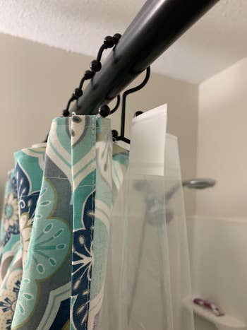 A reviewer's shower using the dual hooks to hang a shower curtain and liner
