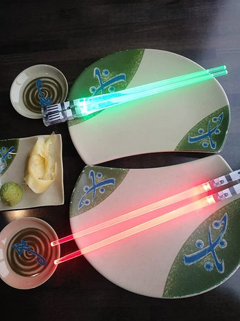 reviewer photo of red and green lightsaber chopsticks lit up on two plates
