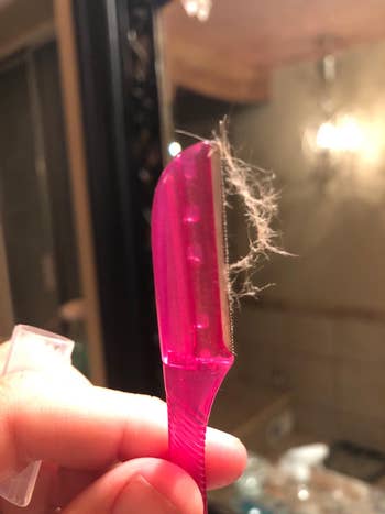 another reviewer photo of pink dermaplaning razor with peach fuzz hair on it