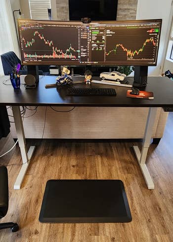 reviewer's mat in front of standing desk that has two monitors on it