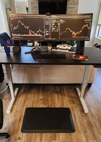 Another reviewer's mat in front of standing desk that has two monitors on it