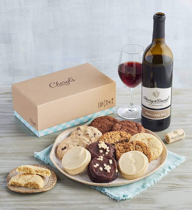 an assortment of cookies on a plate and a bottle of red wine