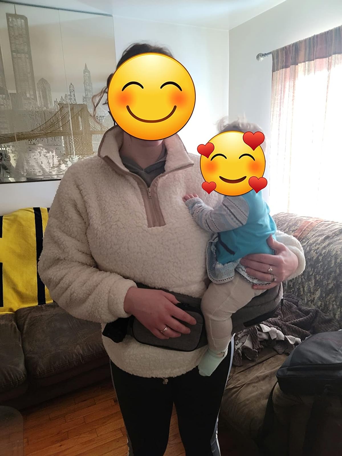 Adult in a cozy pullover holding a happy baby dressed in a blue outfit with a tushbaby attachment