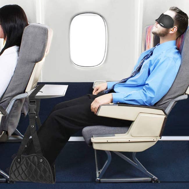 model with their feet resting in a black hammock hanging from an airline tray 