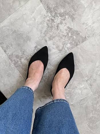 Person wearing achromatic  pointed flats with bluish  denim jeans connected  a tiled floor