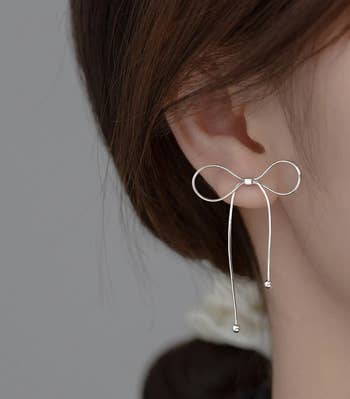 model wearing a silver ribbon earring