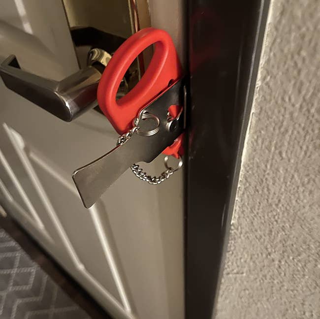 a red portable lock inserted into a door jamb to prevent it from opening
