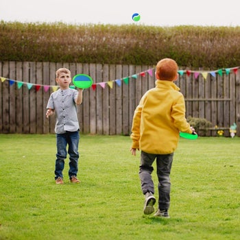 two young children playing with the toss and catch set