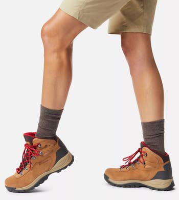 a model wearing the hiking boot in Cognac with red laces