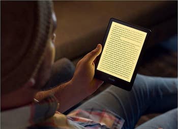 Person reading on a Kindle, showcasing the device's screen and portability for an article on e-readers