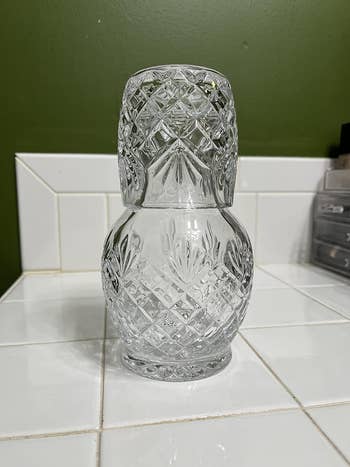 Crystal decanter with intricate patterns, placed on a tiled surface