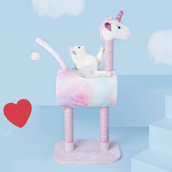 cat inside pastel unicorn with body made out of tunnel and legs and neck scratchers and a toy hanging from tail